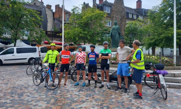 Sur une place, les participants en tenue de cycliste alignés pour la photo officielle au départ