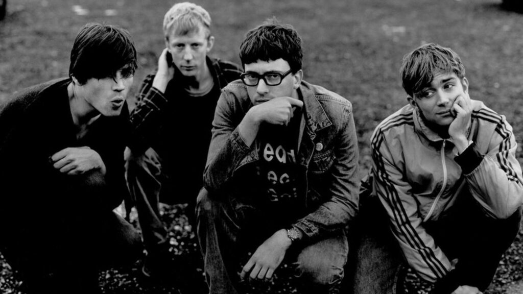 1. Trouvez un concept, même simple Non, il ne faut pas un budget de clip de Beyoncé. Mais il faut une idée. Une couleur dominante, un décor particulier, un objet qui raconte quelque chose de vous. Les Ramones avaient leurs blousons, Blur avait son côté boys next door british. Vous, vous avez quoi ? 2. Choisissez un photographe qui comprend votre univers Pas “un pote qui a un appareil photo”. Un photographe qui sait travailler la lumière, qui connaît la scène musicale et qui saura capter ce qui vous rend unique. Le brief est important : montrez-lui vos influences, vos pochettes, vos clips. 3. Travaillez la lumière La lumière, c’est 50 % d’une bonne photo. Évitez les néons blancs de parking ou le soleil écrasant de midi. Une lumière douce, en fin de journée, ou un éclairage maîtrisé en intérieur change tout. 4. Pensez à la composition Tout le monde debout en ligne, c’est l’ennui. Jouez sur les hauteurs, les plans rapprochés, les décalages. Utilisez l’espace : escaliers, structures, éléments urbains ou naturels. 5. Racontez quelque chose Votre musique est sombre ? Votre photo doit l’être aussi. Vous faites du punk joyeux ? Montrez-le. L’image doit refléter votre son et votre personnalité, pas juste “quatre personnes qui posent”. 6. Évitez les clichés… sauf si vous les détournez La photo devant un mur de briques, la pose bras croisés… Si vous le faites, faites-le à fond et avec humour. Sinon, passez à autre chose. En résumé : une bonne photo de groupe, ce n’est pas forcément cher ni compliqué. C’est juste réfléchi. Et la prochaine fois qu’on vous proposera de “faire vite fait une photo pour le press kit”, rappelez-vous que cette image pourrait décider si votre mail est ouvert… ou pas.